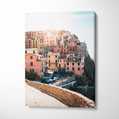 Vertical canvas wall art featuring colorful coastal buildings on a cliff with bright sky backdrop.