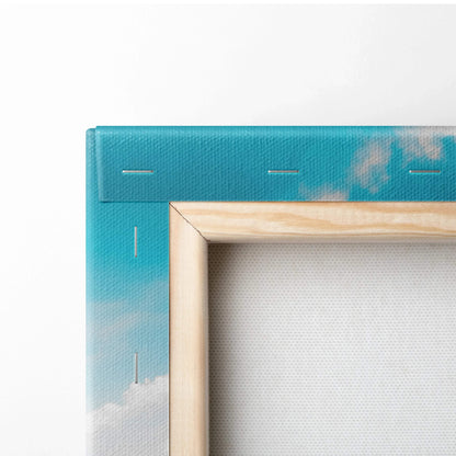Close-up of stretched canvas wall art with blue sky and clouds design, wooden frame edges visible.