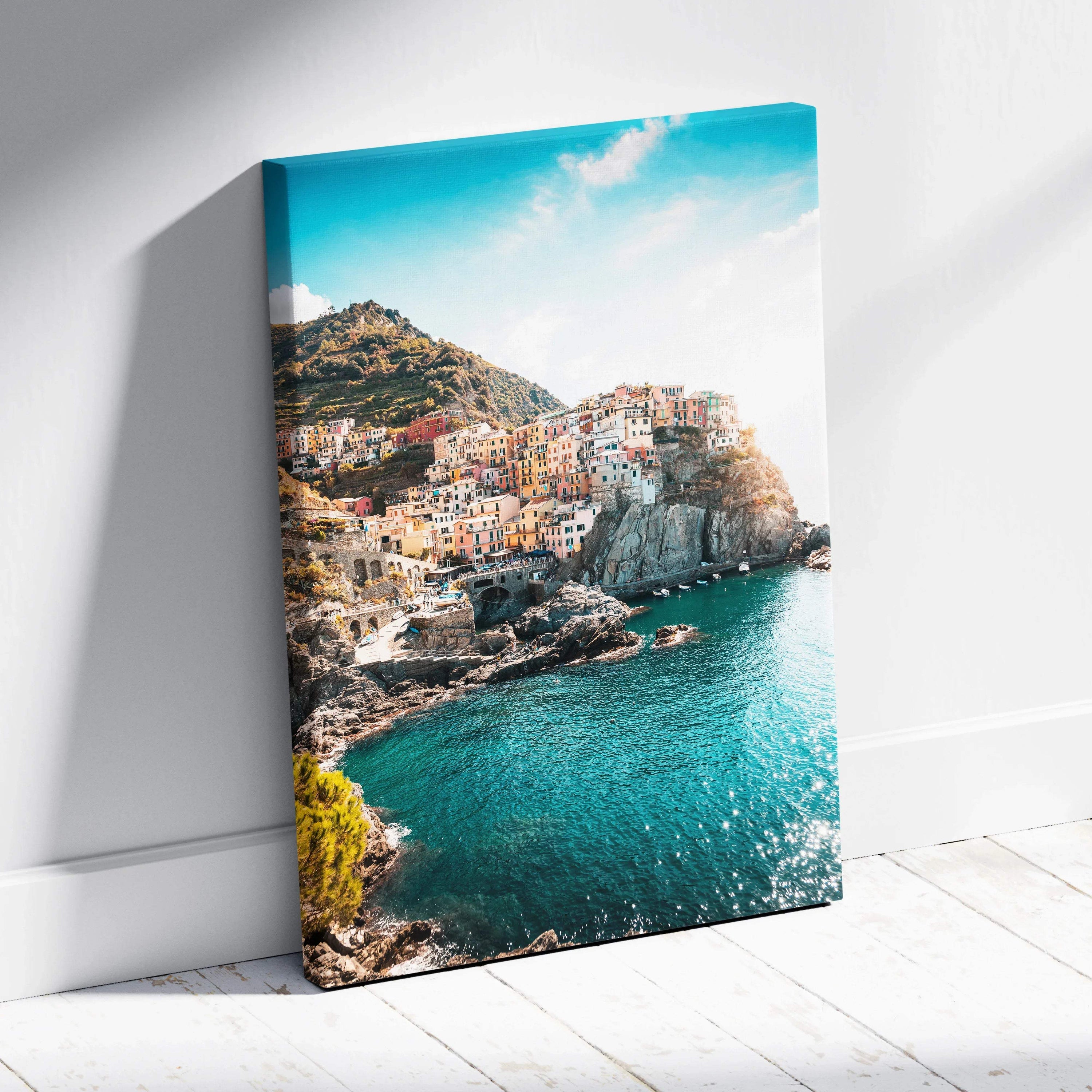 Canvas wall art featuring colorful buildings on a rocky coastline with bright blue sky and sea.