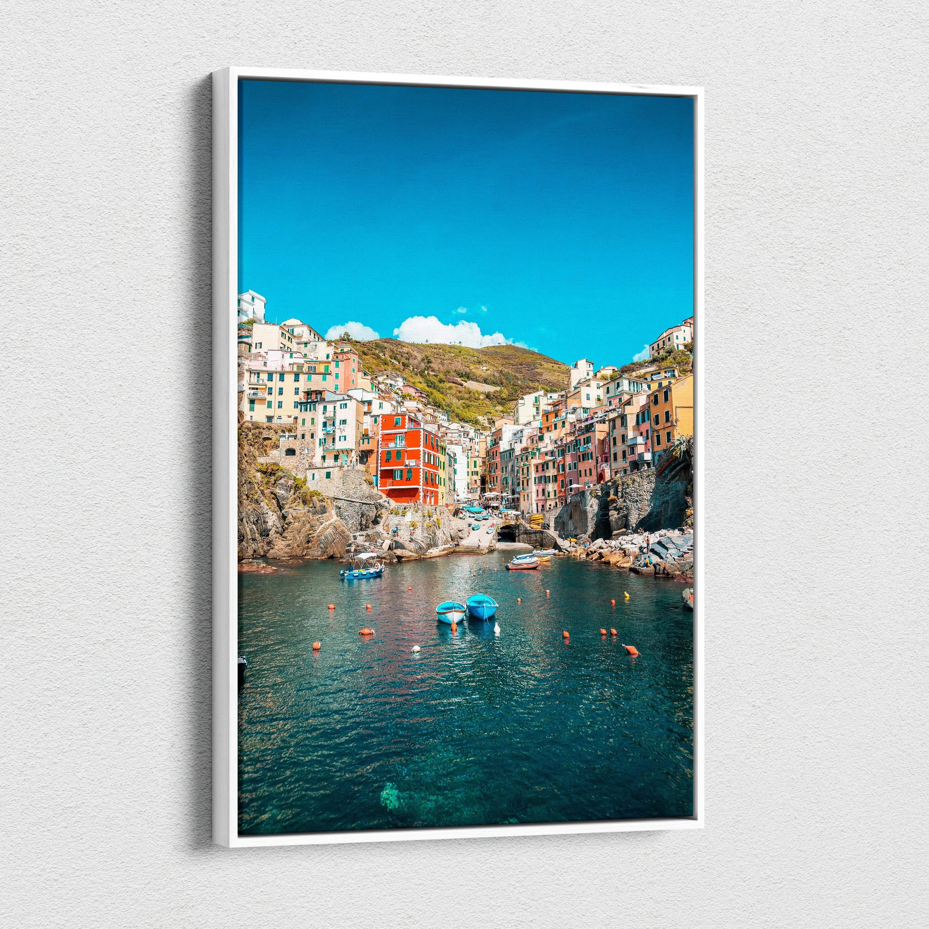 Vertical canvas wall art featuring colorful coastal buildings and tranquil blue water under a bright sky.