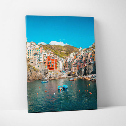 Canvas wall art featuring colorful coastal buildings and clear blue sky over calm harbor water.