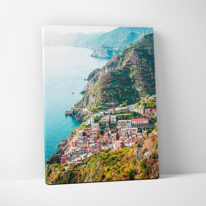 Canvas wall art print featuring a colorful seaside village built on lush green cliffs against a blue ocean backdrop.