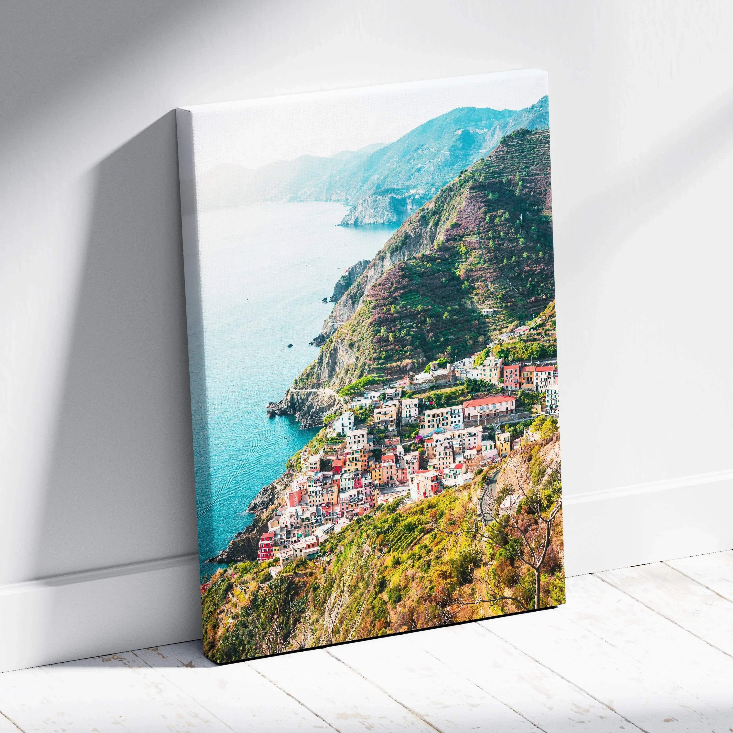 Canvas wall art featuring a vibrant coastal village nestled on green cliffs beside blue ocean waters.