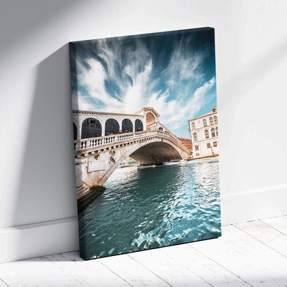 Canvas wall art featuring a detailed digital painting of a white arched bridge over blue-green water under a cloudy sky.