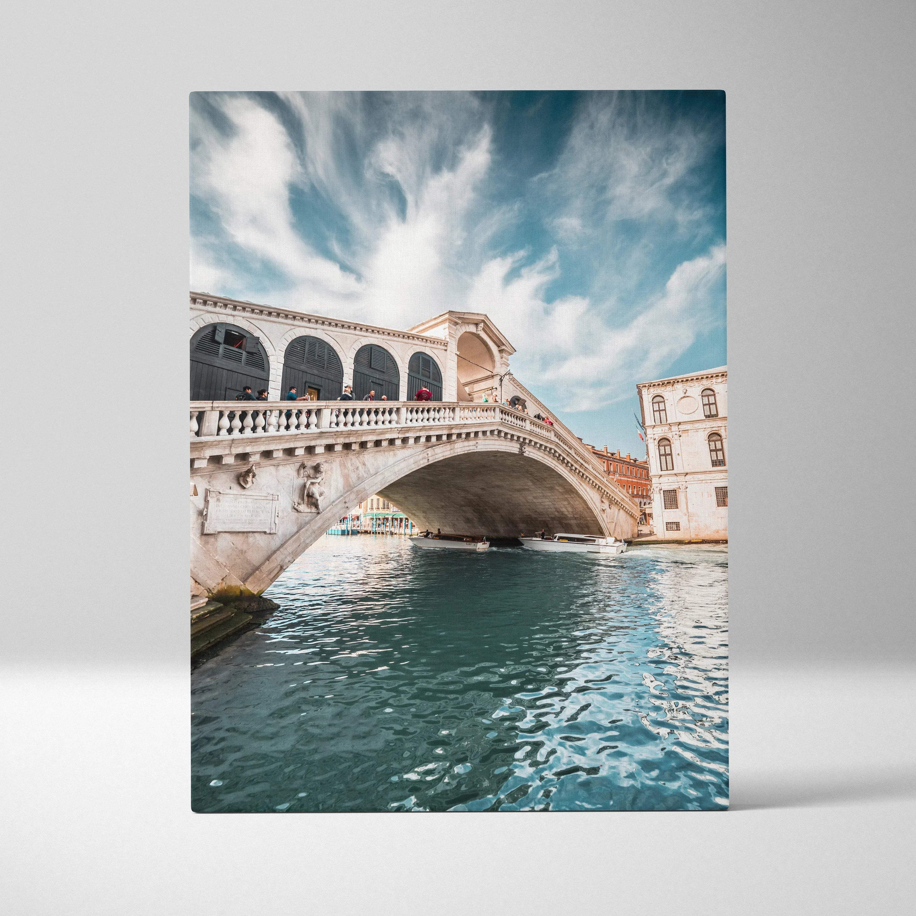 Vertical canvas wall art featuring the Rialto Bridge over a Venetian canal under a bright sky.