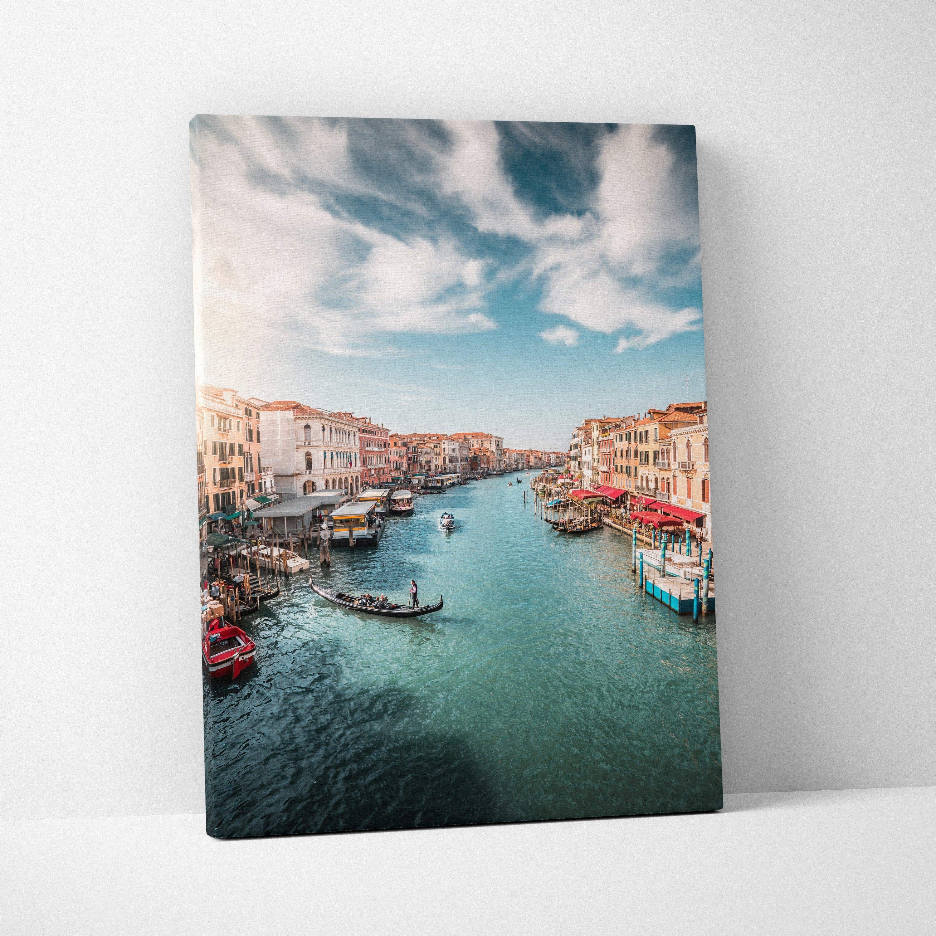 Vertical canvas wall art featuring a serene canal with boats and historic buildings under a blue sky.