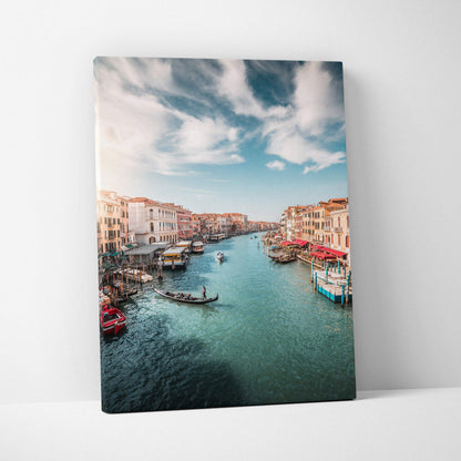 Vertical canvas wall art featuring a serene canal with boats and historic buildings under a blue sky.