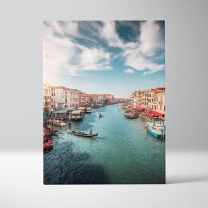 Vertical canvas wall art featuring a vibrant canal scene with buildings and boats under a blue sky.