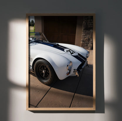 Shelby Cobra car poster with white body and black racing stripes, stylish wall art in wooden frame.