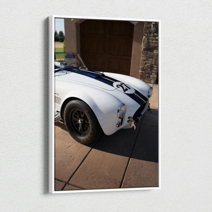 Vertical canvas art featuring a white Shelby Cobra with black racing stripes in a driveway setting.