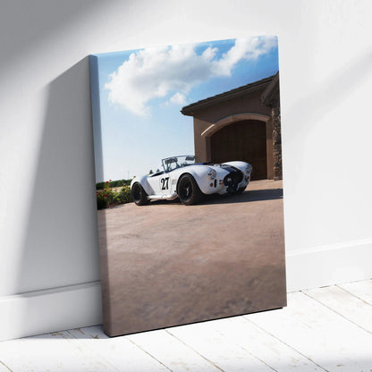 Vertical canvas art featuring a white Shelby Cobra parked on a driveway under a partly cloudy blue sky.