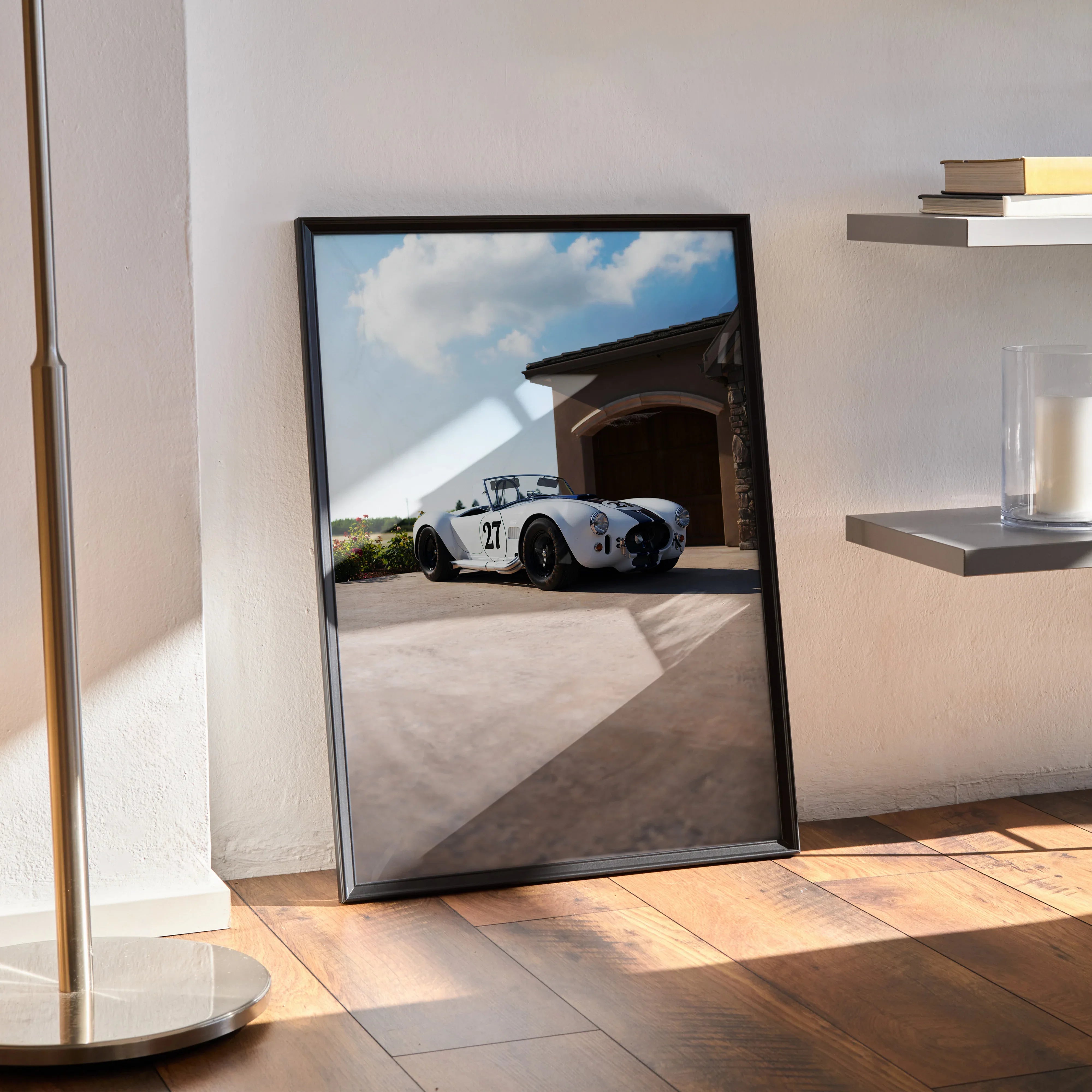 Shelby Cobra poster wall art featuring a classic white sports car parked by a garage under blue sky.