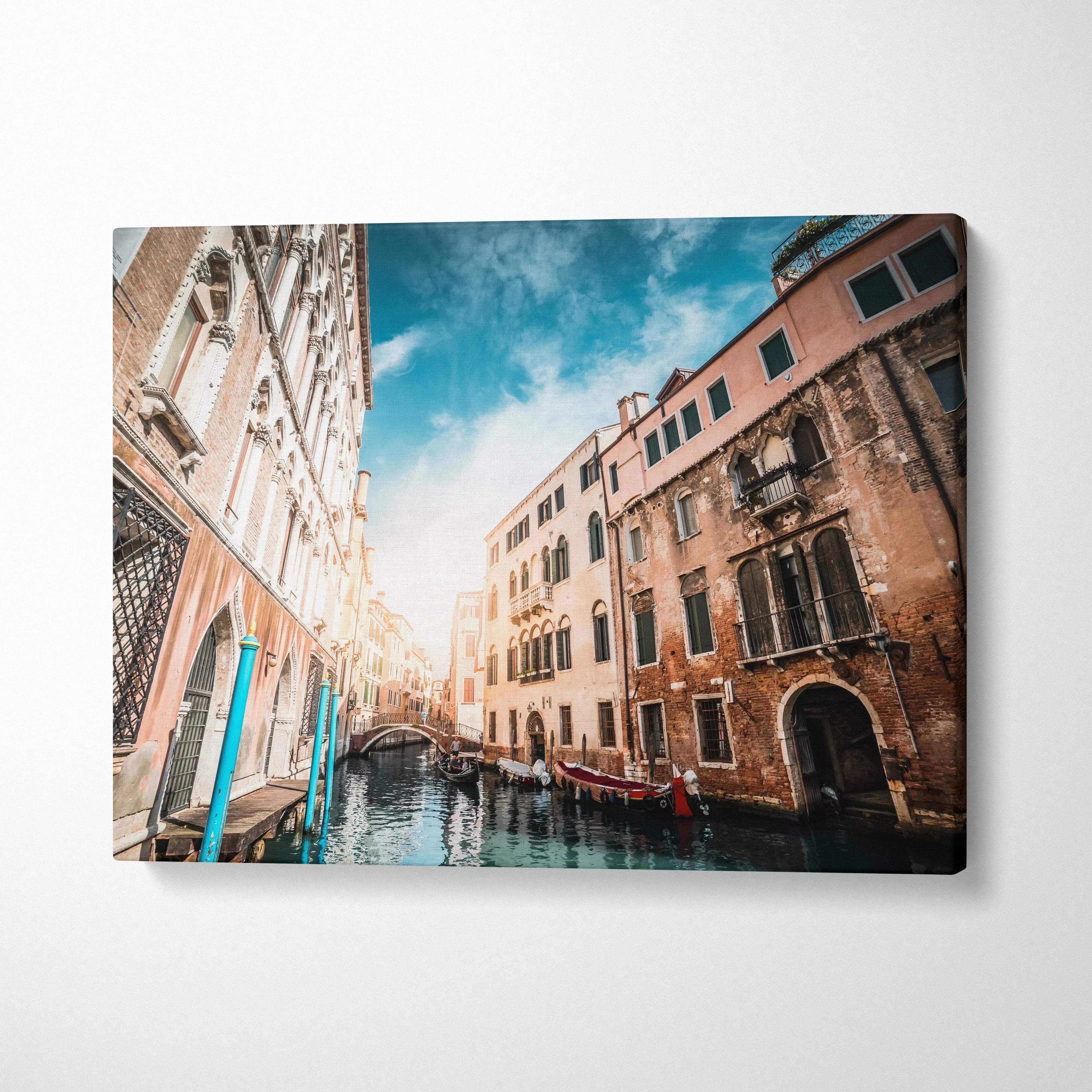 Venetian canal scene canvas wall art featuring old buildings and gondolas under blue sky.