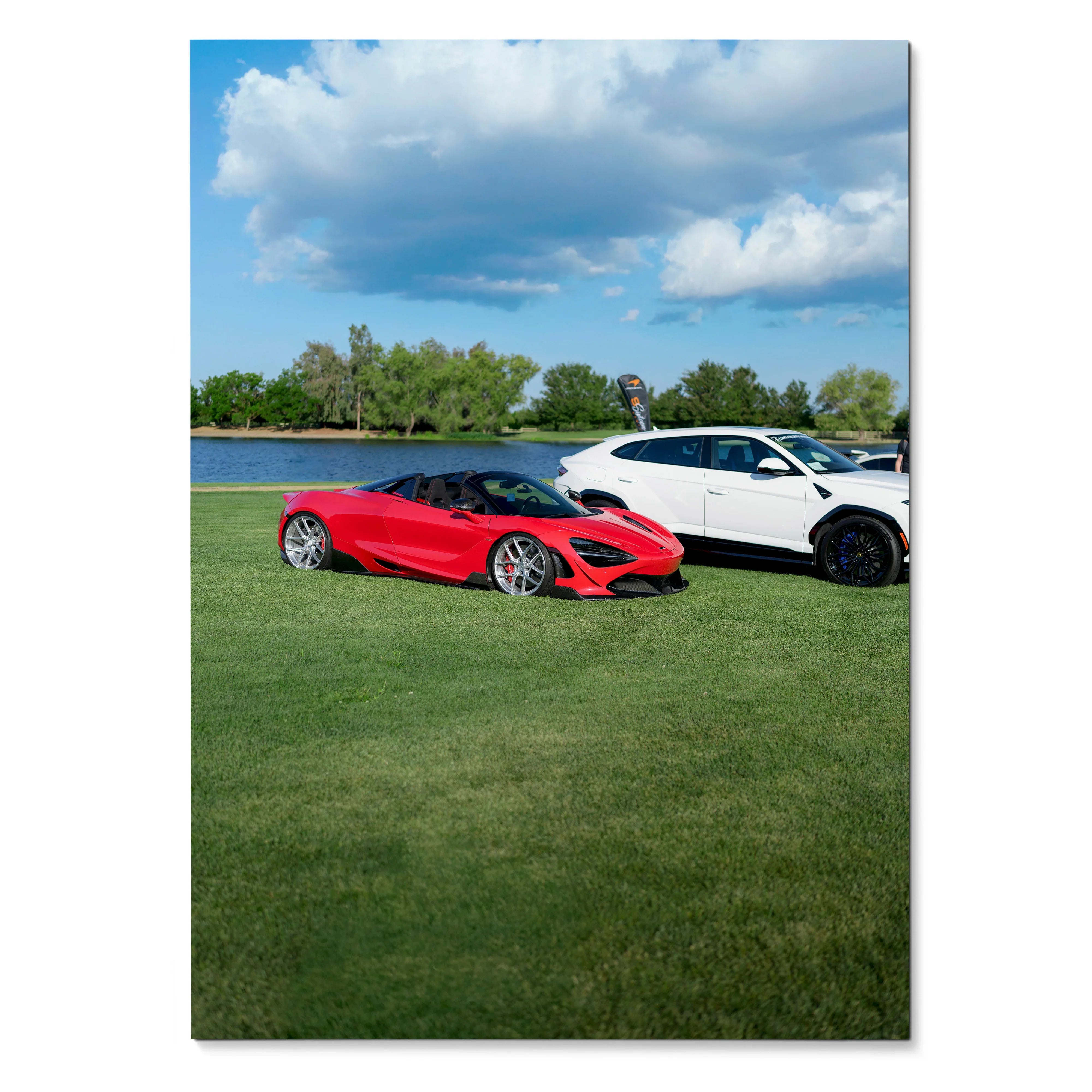 McLaren 720S red sports car and white SUV on grass by lake poster wall art.