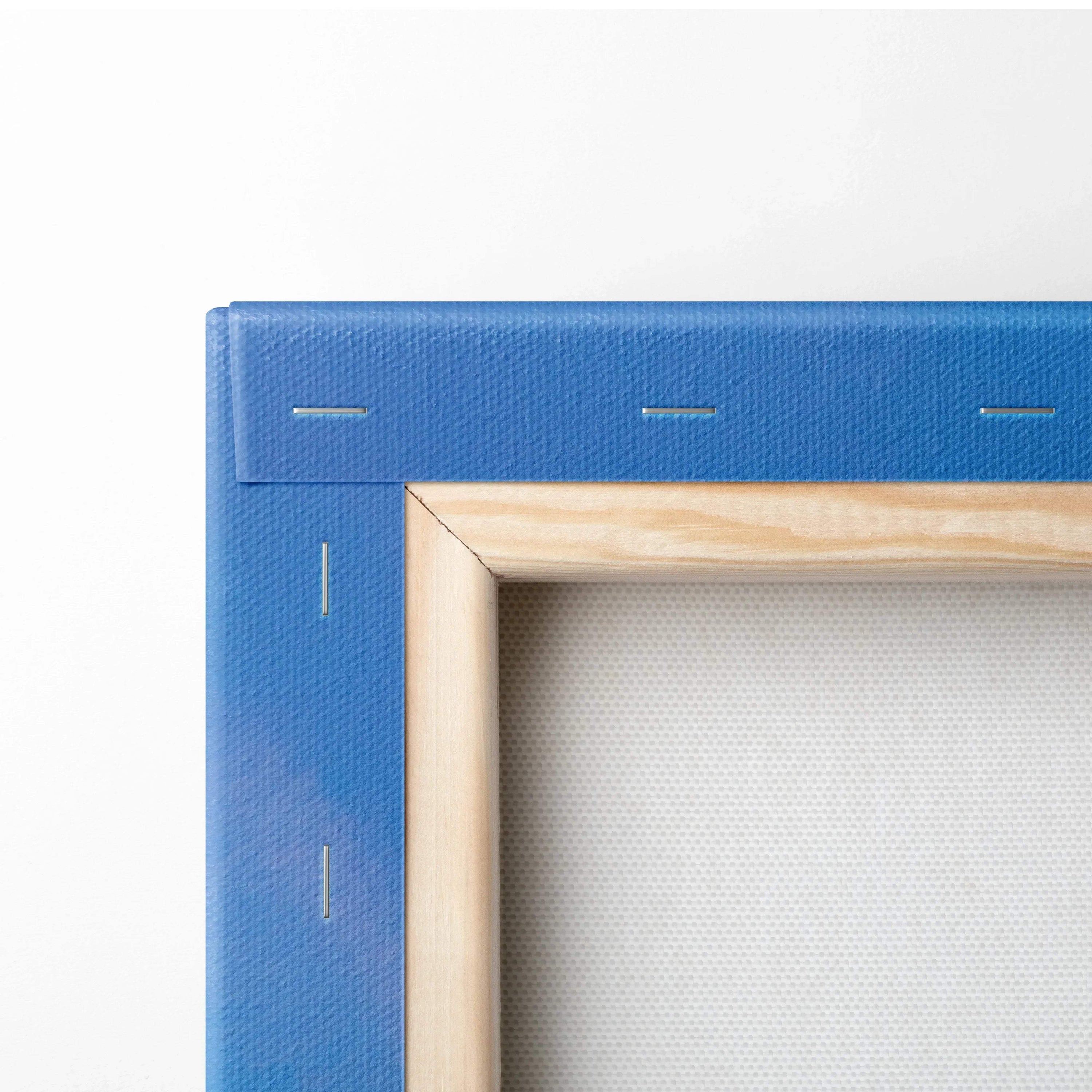 Corner of wooden frame with blue canvas stretched and stapled for vertical wall art canvas print.
