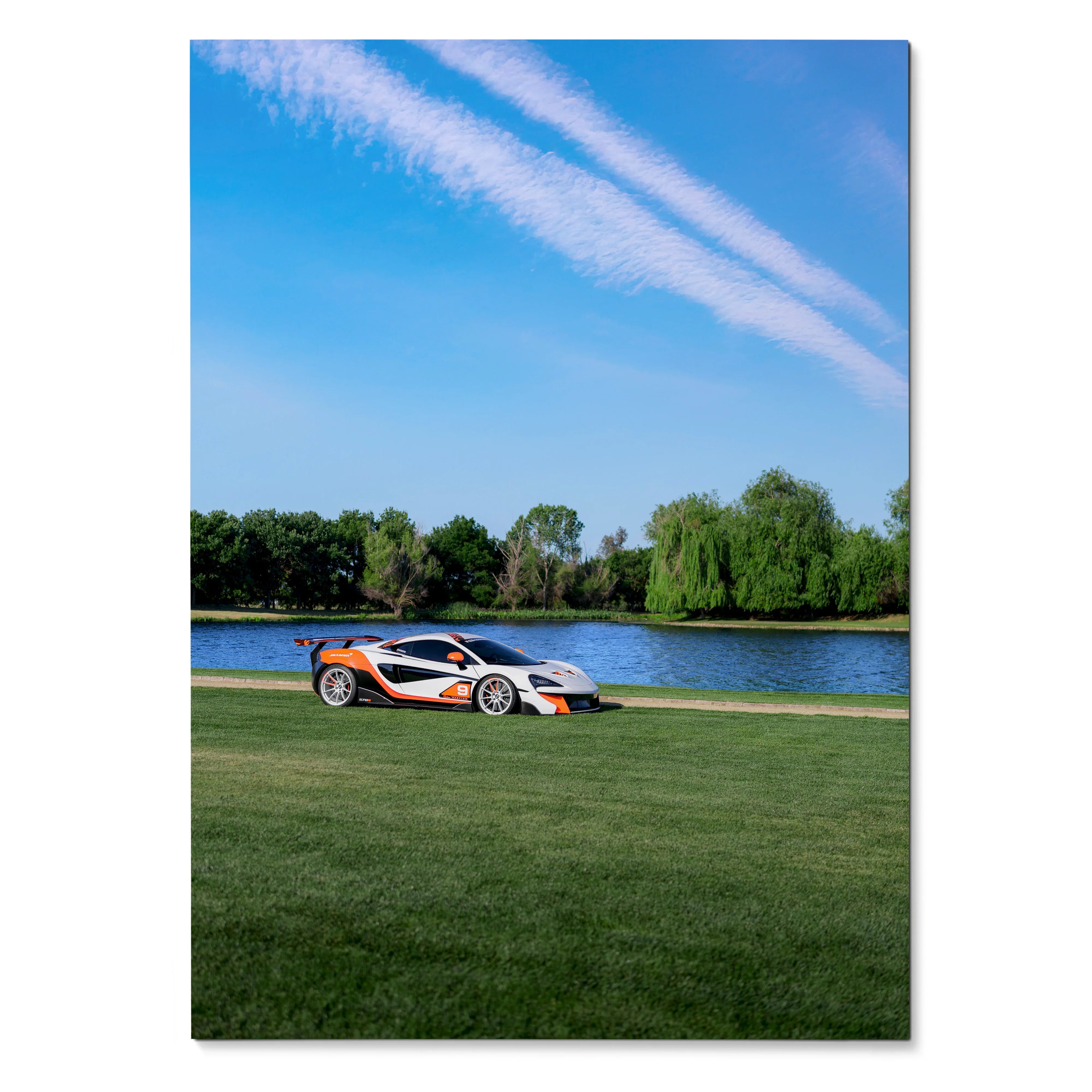 McLaren 570S sports car parked on grass near river under blue sky poster wall art.