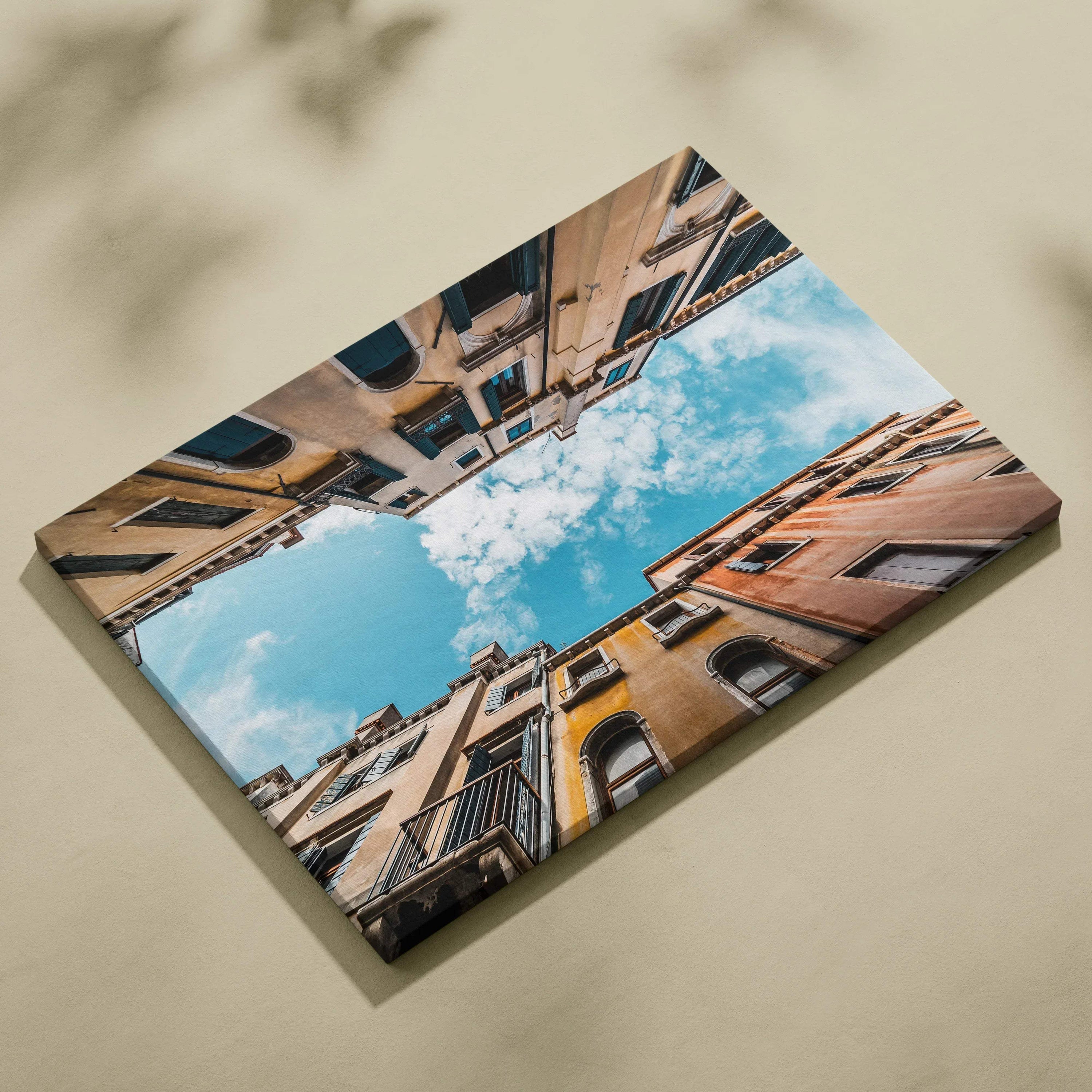 Premium canvas wall art featuring upward view of colorful architecture under blue sky with clouds.
