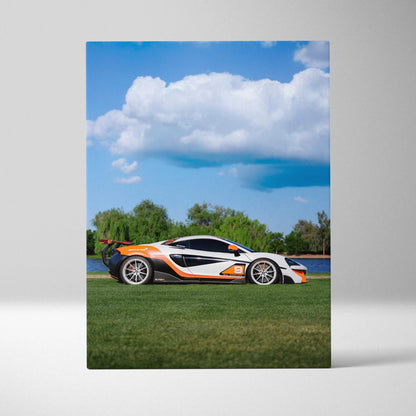Vertical canvas art featuring a white and orange McLaren 570S sports car against a blue sky with clouds and green grass.