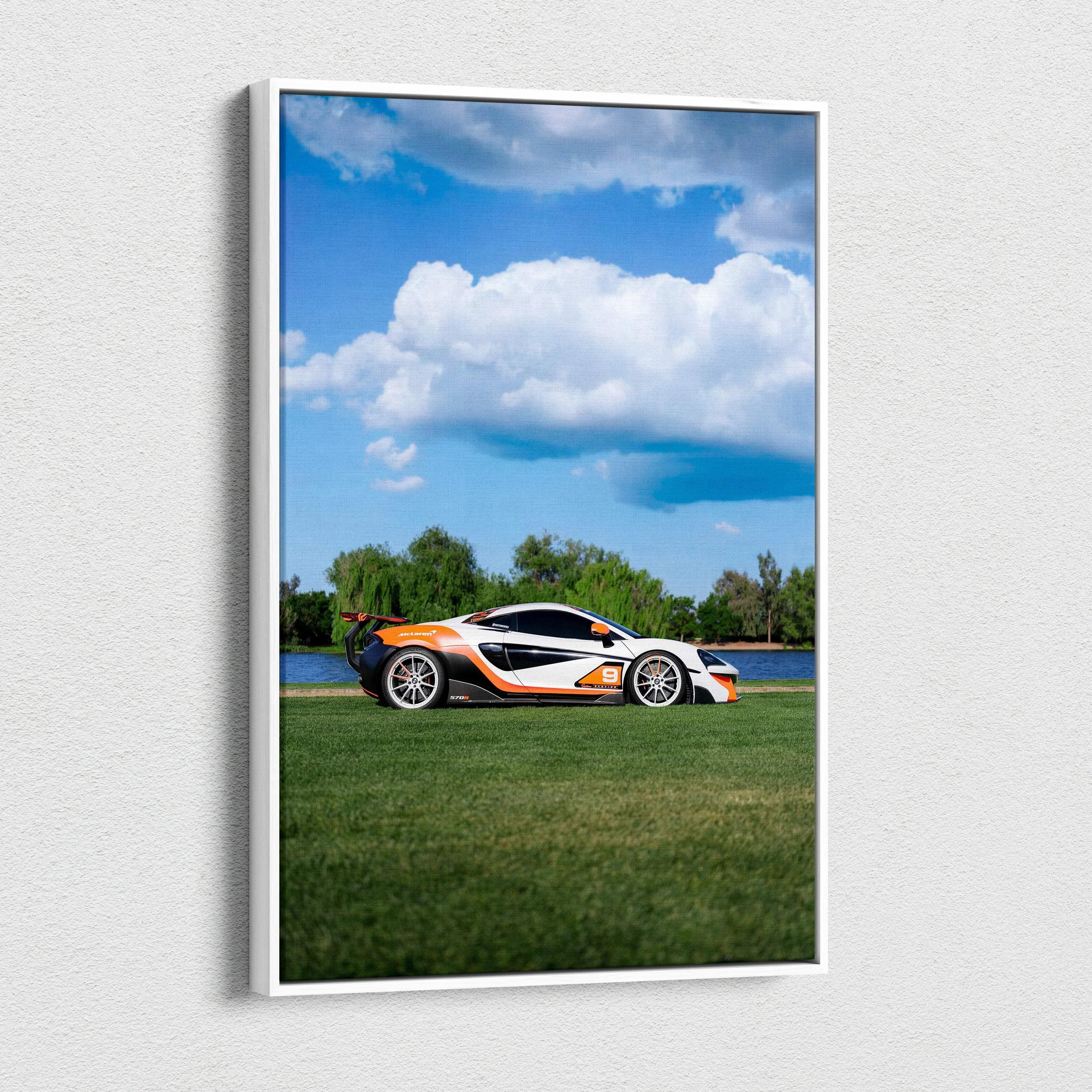 Vertical canvas art of a white and orange McLaren 570S sports car on grass under a blue sky with clouds.