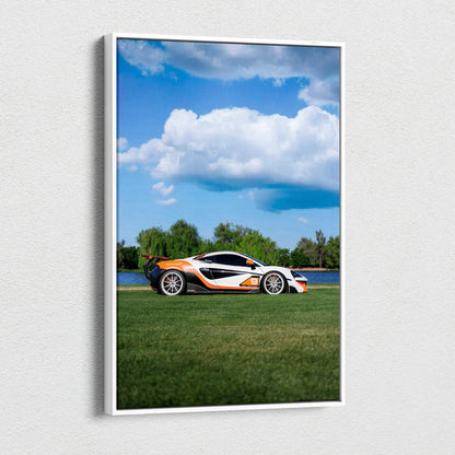 Vertical canvas art of a white and orange McLaren 570S sports car on grass under a blue sky with clouds.