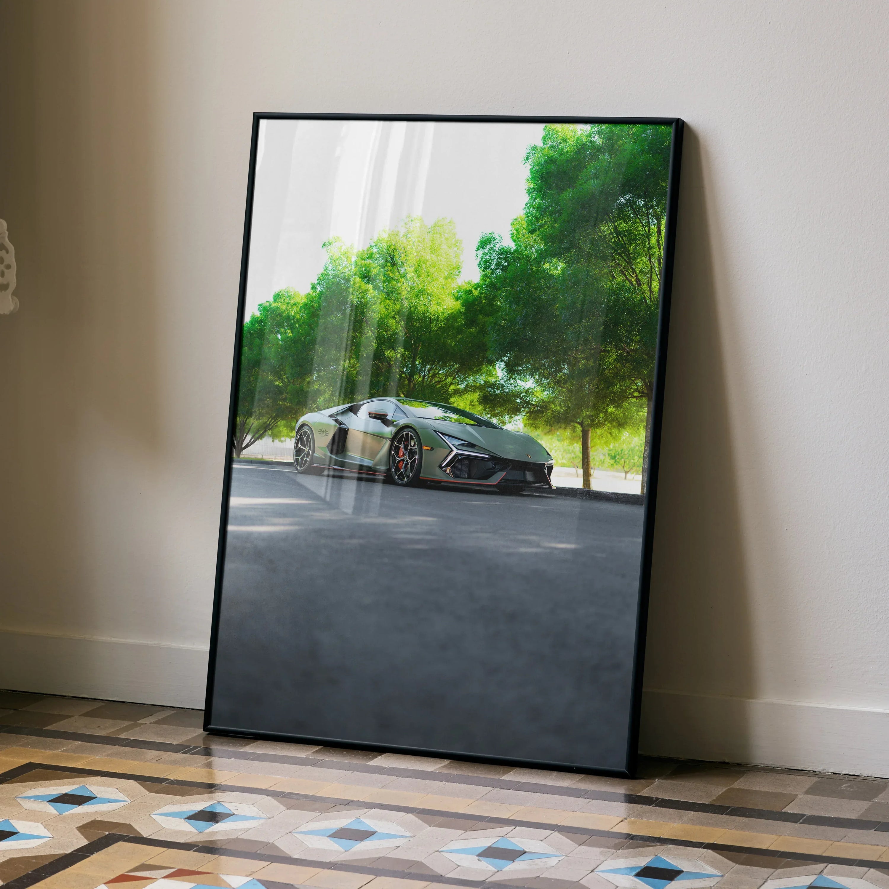 Lamborghini Revuelto poster leaning against wall with lush green trees and tiled floor wall art.