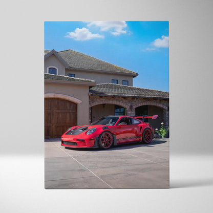 Vertical canvas art of a red Porsche 911 GT3 RS parked in front of a beige house under blue sky wall art.