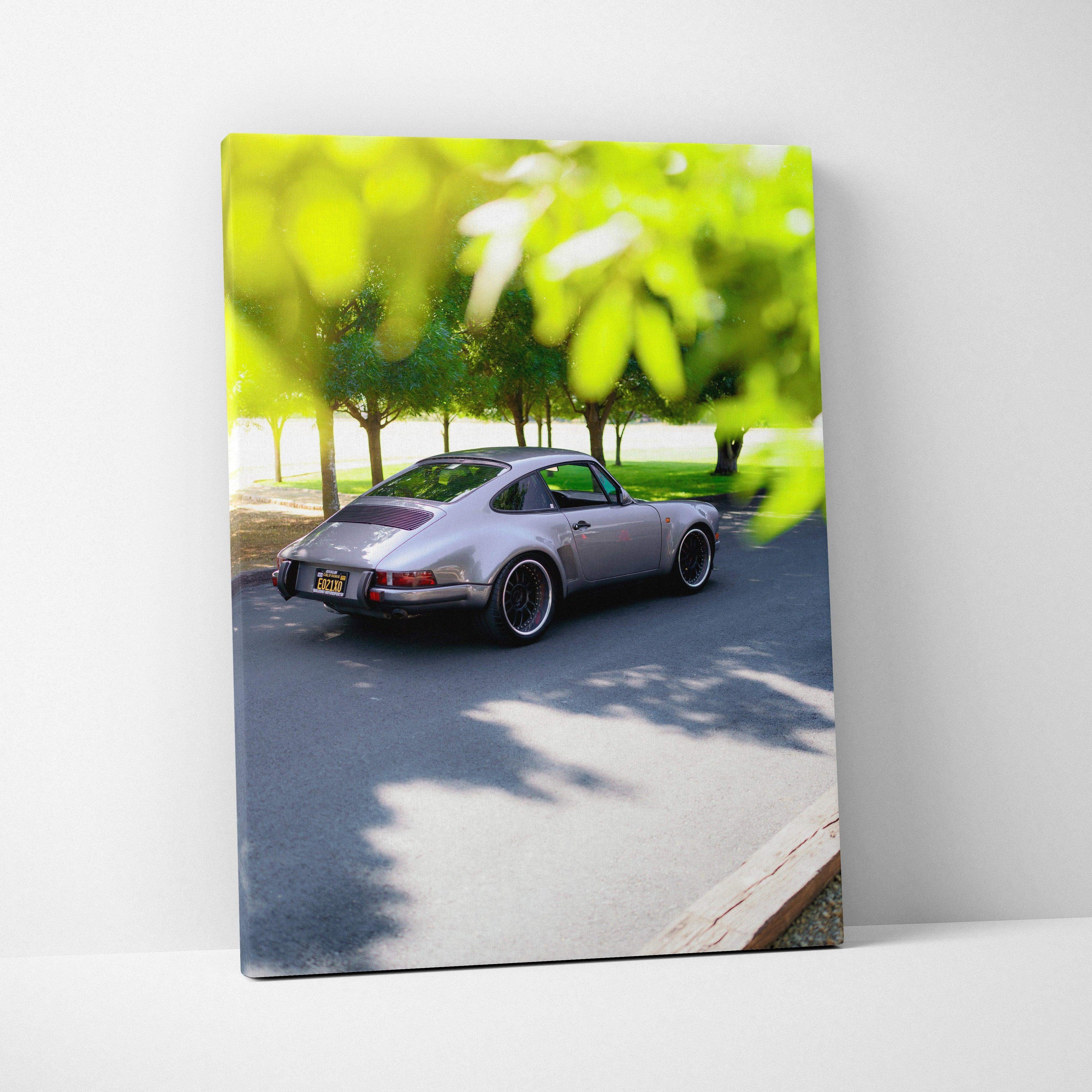 Porsche 911 classic car driving on tree-lined road canvas wall art vertical print.