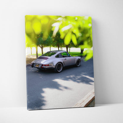 Porsche 911 classic car driving on tree-lined road canvas wall art vertical print.