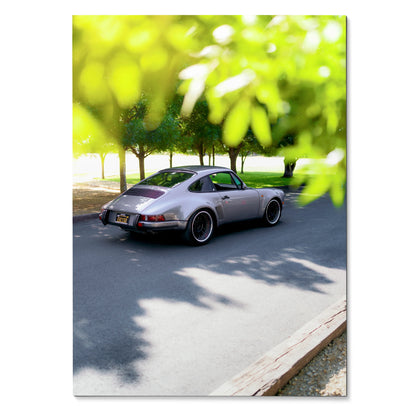 Porsche 911 classic gray car parked on street surrounded by green tree foliage wall art poster.