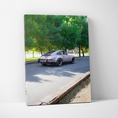 Porsche 911 classic driving on tree-lined road high resolution vertical canvas wall art.