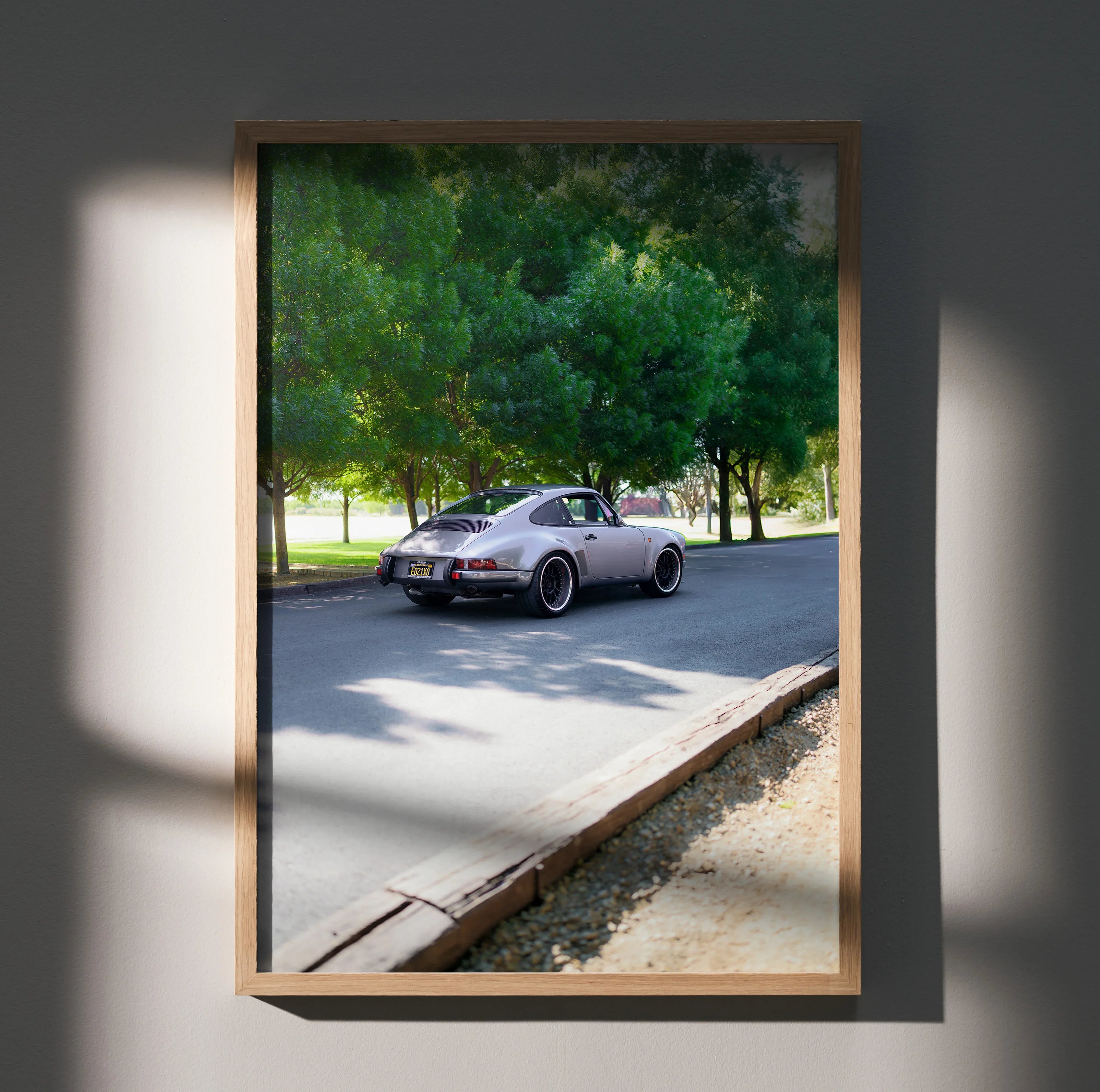 Porsche 911 classic car driving on tree-lined road poster wall art in wooden frame.