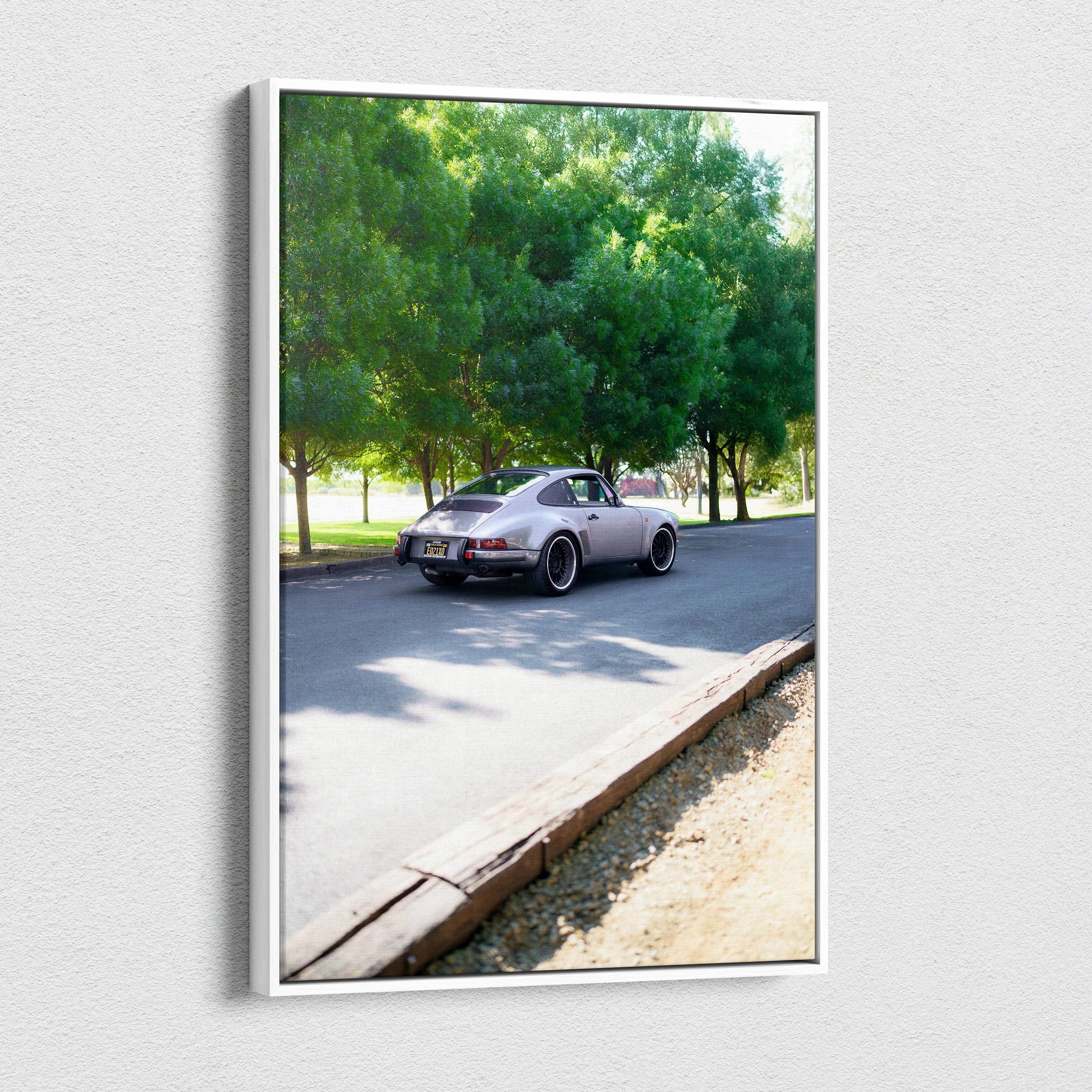 Vertical canvas art featuring a classic Porsche 911 driving past green trees as wall art.