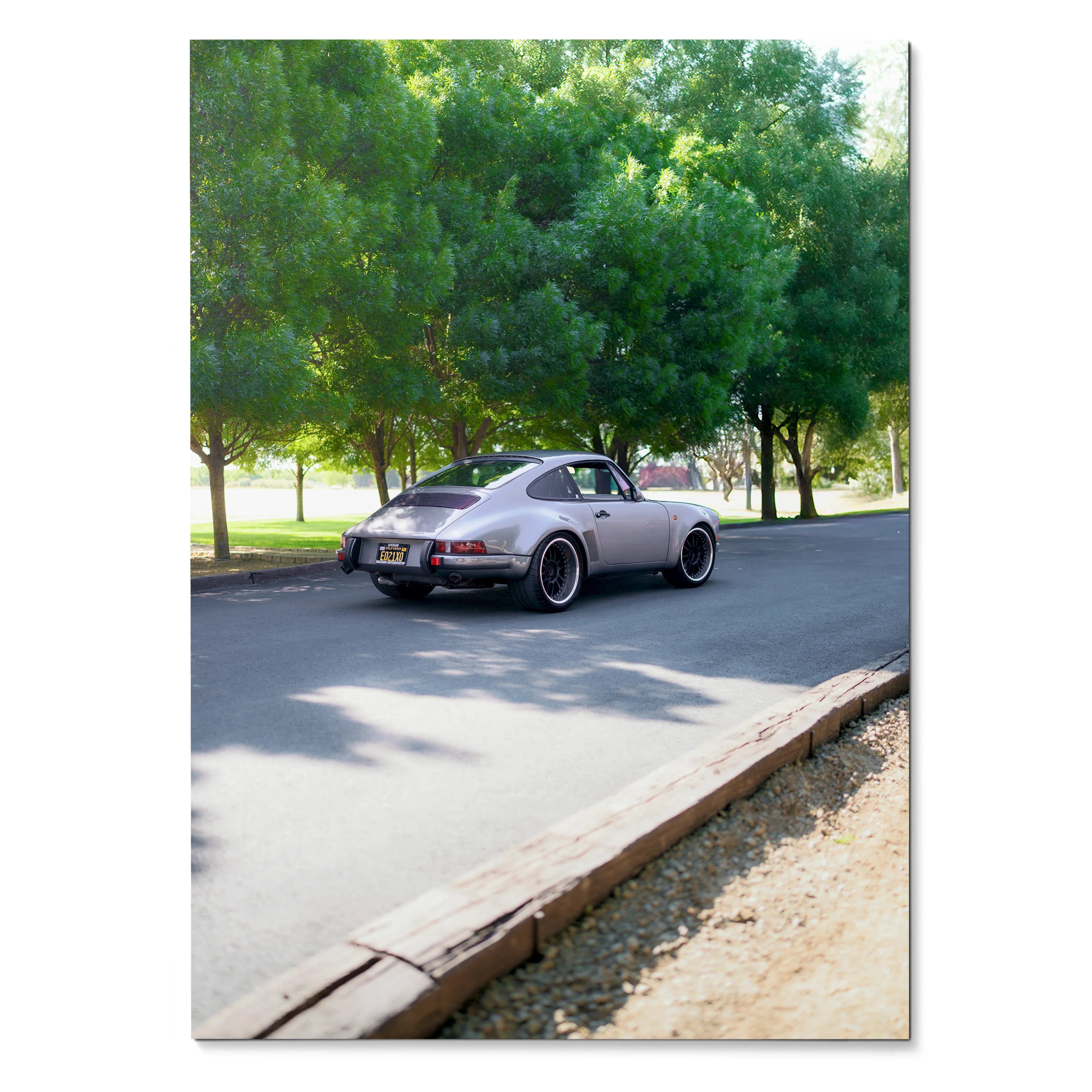 Porsche 911 classic car driving on tree-lined road poster wall art in natural light.