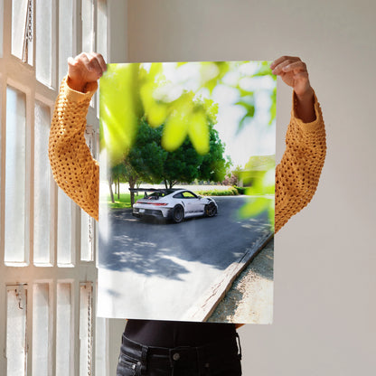 Porsche 911 GT3 RS parked on a tree-lined road poster wall art with vibrant green foliage.