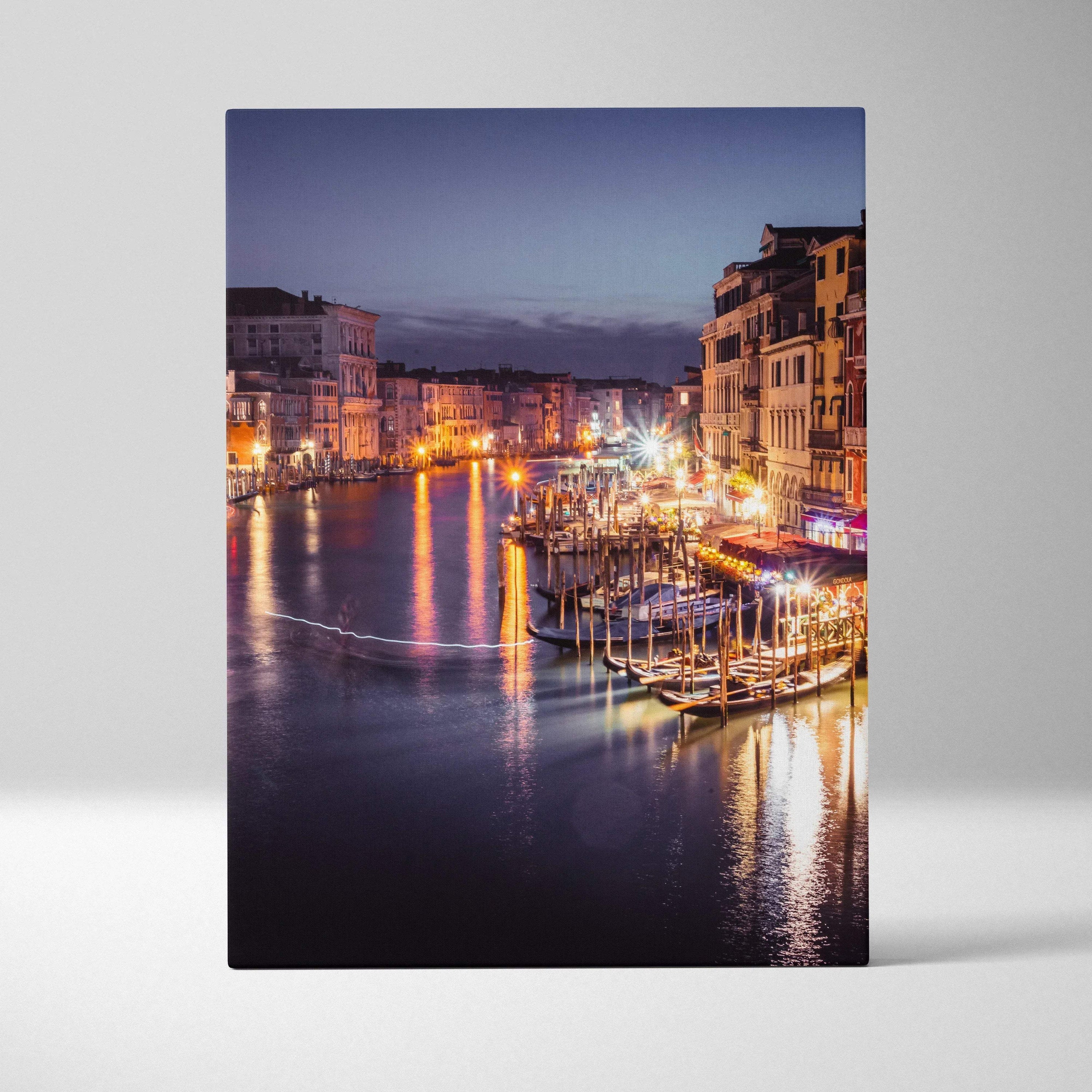 Canvas wall art featuring a glowing urban waterfront with illuminated buildings and boats at dusk.
