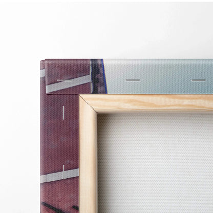 Corner detail of stretched canvas art with natural wood frame and abstract architectural design in muted colors.