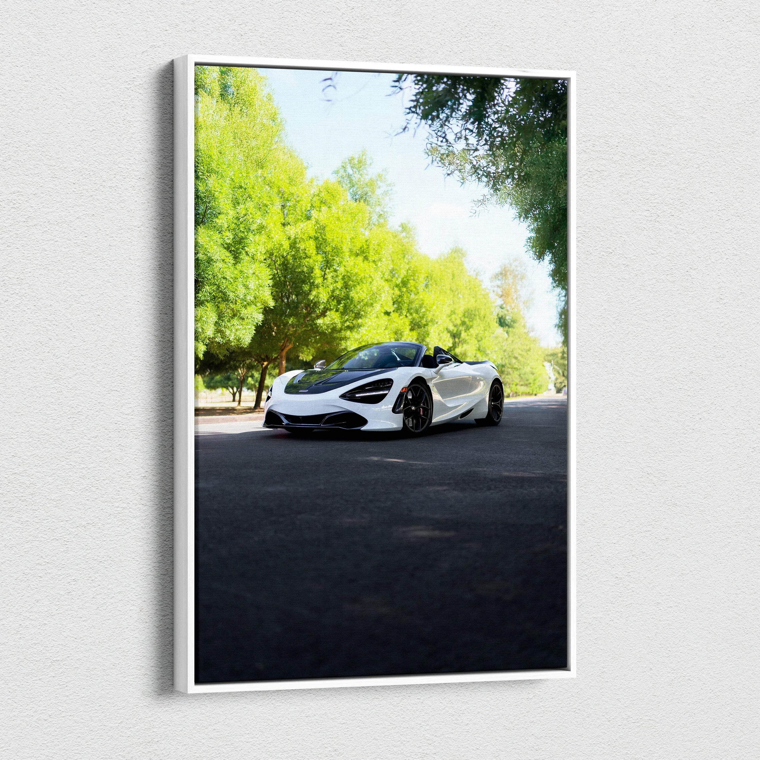 Vertical canvas wall art featuring a white McLaren 720S sports car on a sunlit road surrounded by green trees.