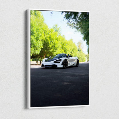 Vertical canvas wall art featuring a white McLaren 720S sports car on a sunlit road surrounded by green trees.