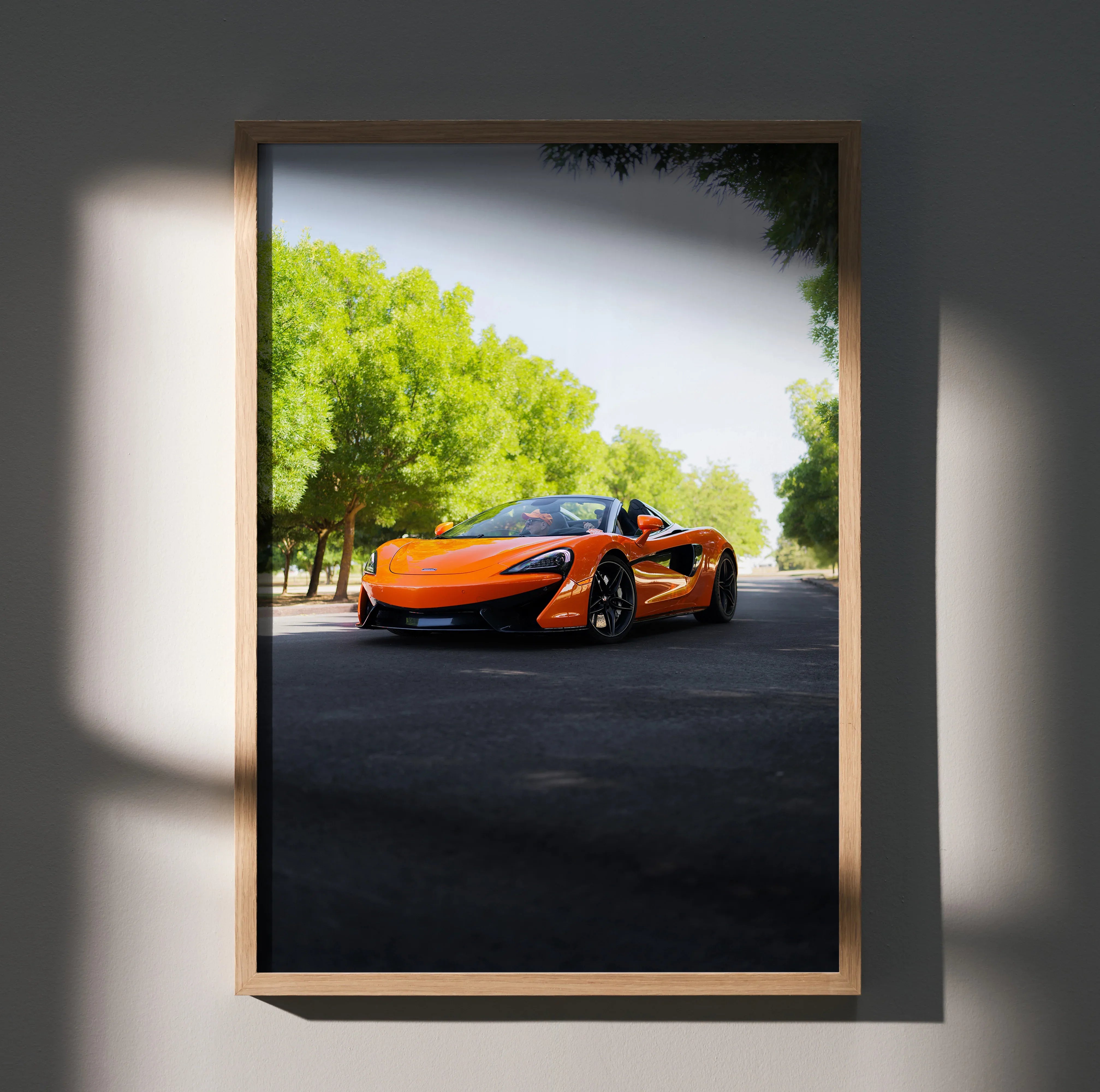 McLaren 570S orange sports car on road with green trees, framed poster wall art.