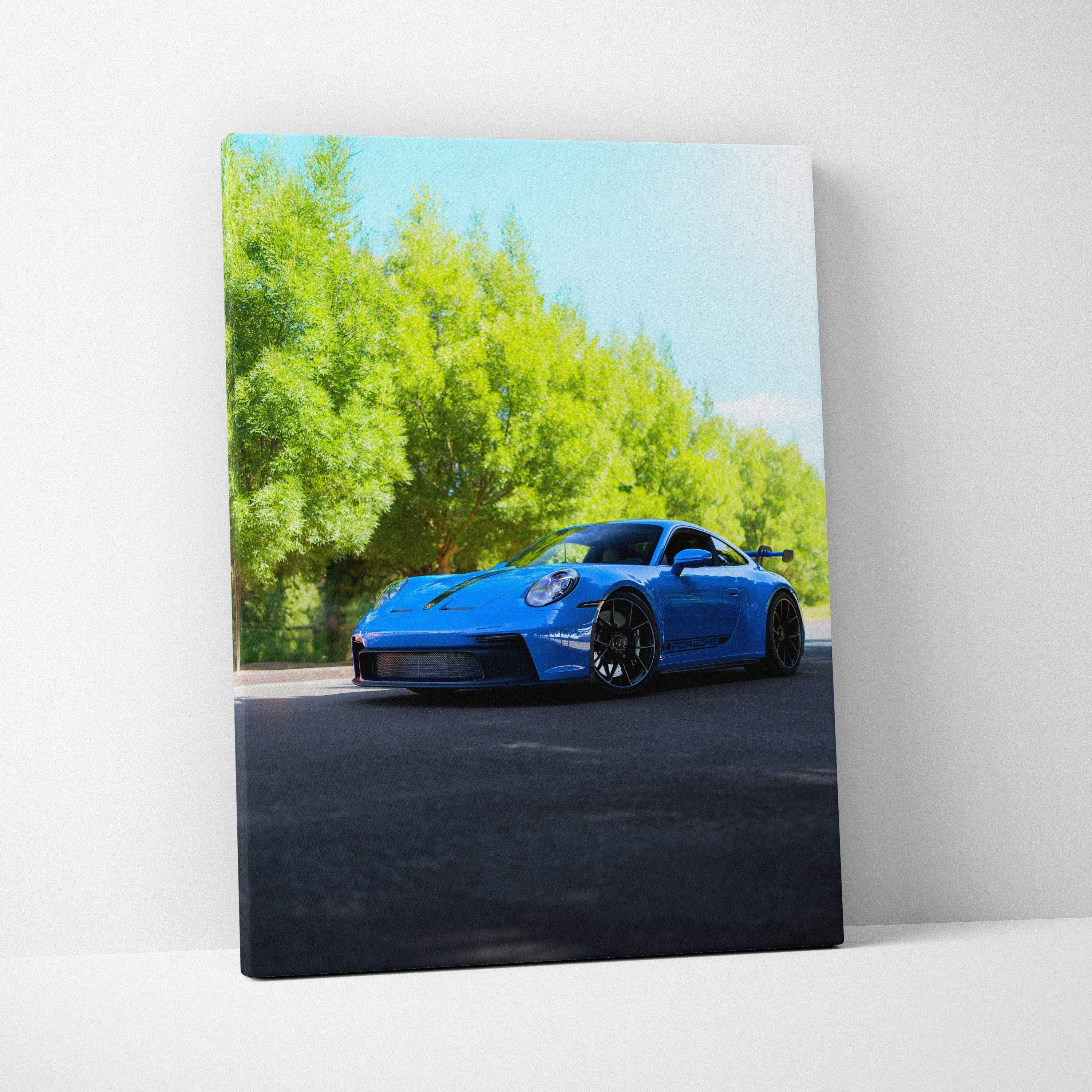Vertical canvas art featuring a blue Porsche 911 GT3 parked on road with green trees background.