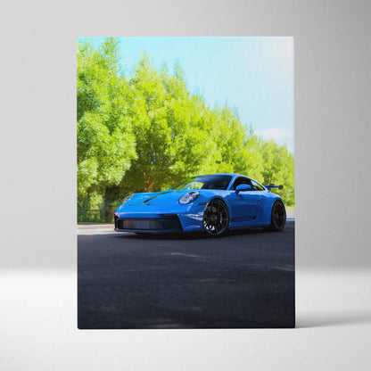 Blue Porsche 911 GT3 parked on blacktop under green trees canvas wall art vertical print.