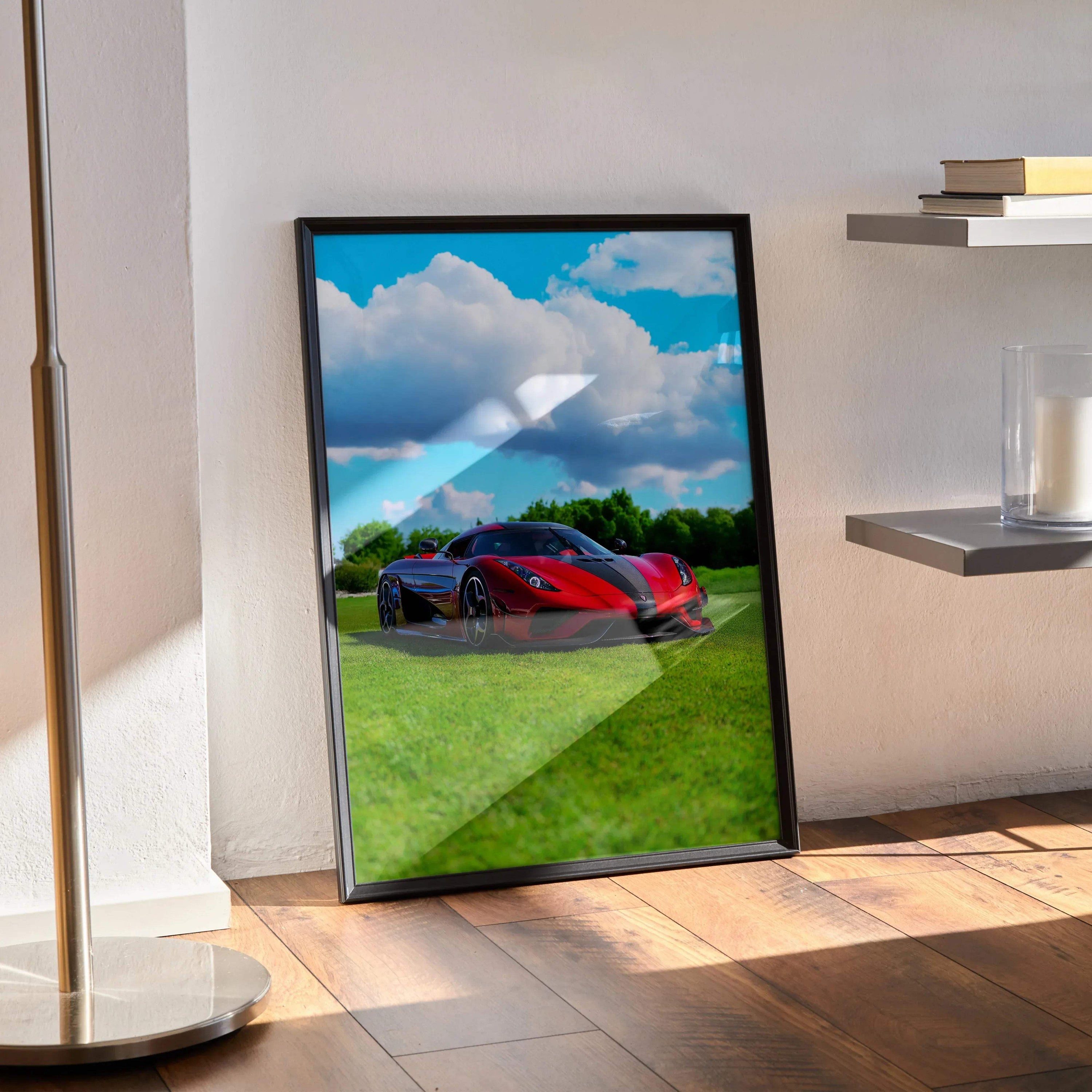 Koenigsegg Regera car poster with red sports car on green grass under blue sky wall art in black frame.