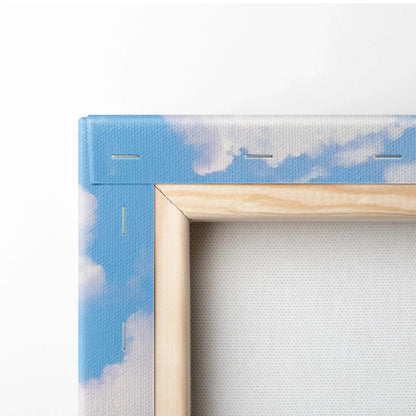 Close-up of wooden frame corner with blue sky and cloud design on vertical canvas wall art.