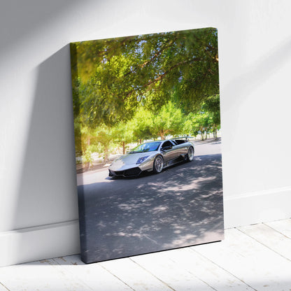 Vertical canvas wall art featuring a silver Lamborghini Murcielago under green trees with dappled sunlight.