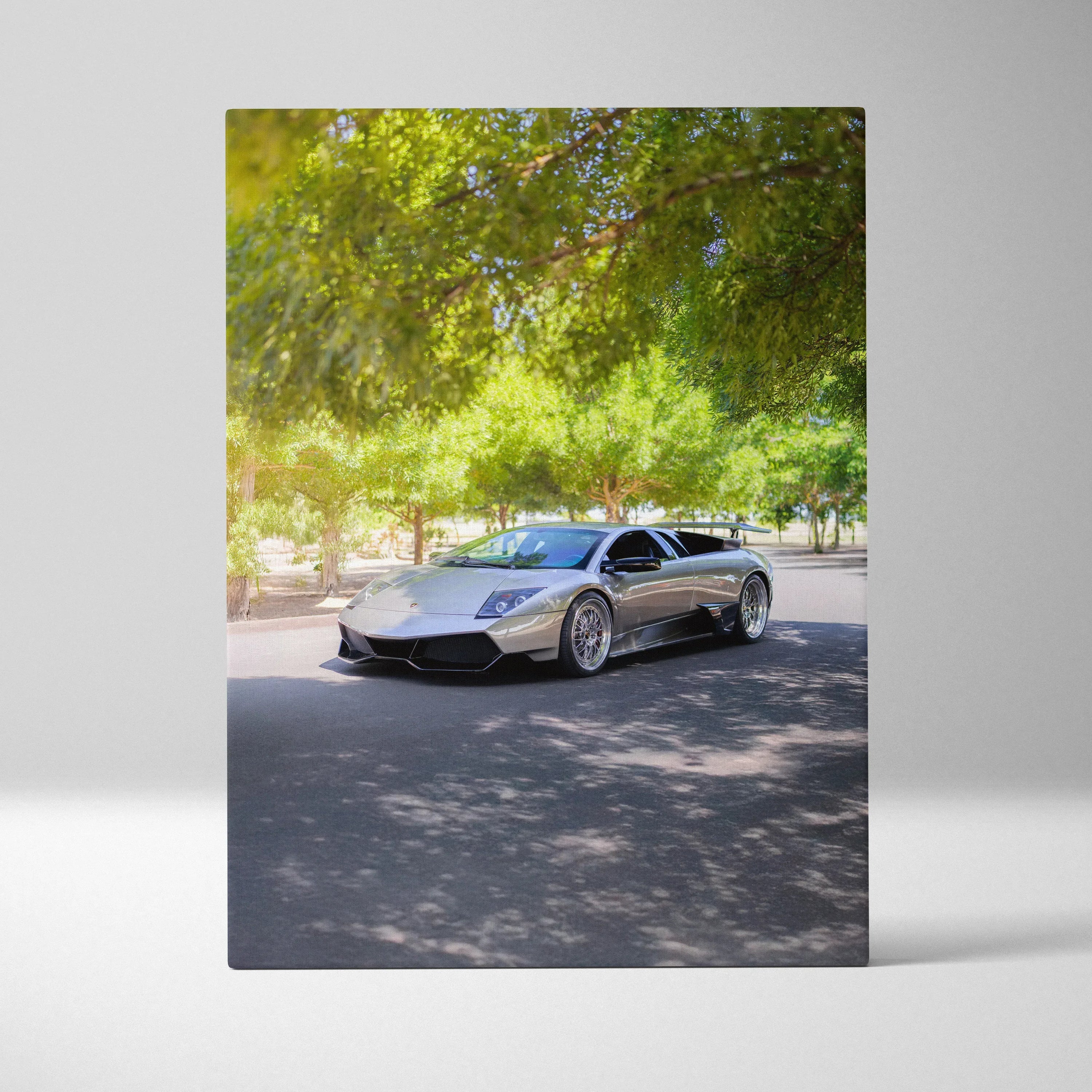Lamborghini Murcielago parked under sunlit green trees on high resolution vertical canvas wall art.