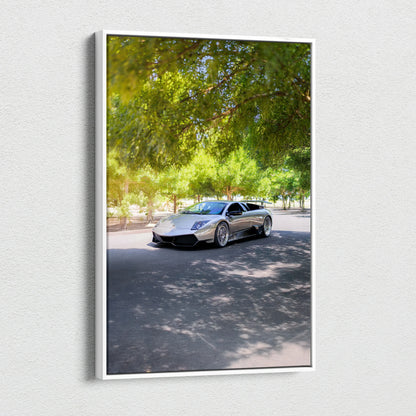 Vertical canvas wall art featuring a silver Lamborghini Murcielago under green leafy trees.