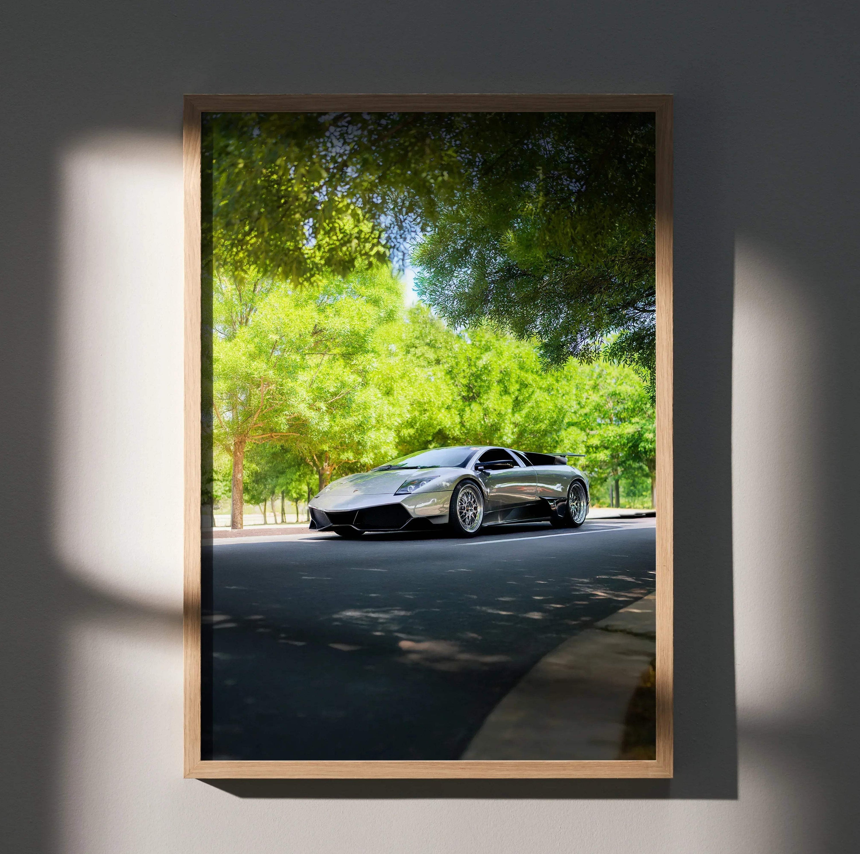 Lamborghini Murcielago poster wall art featuring sleek silver sports car under green trees.