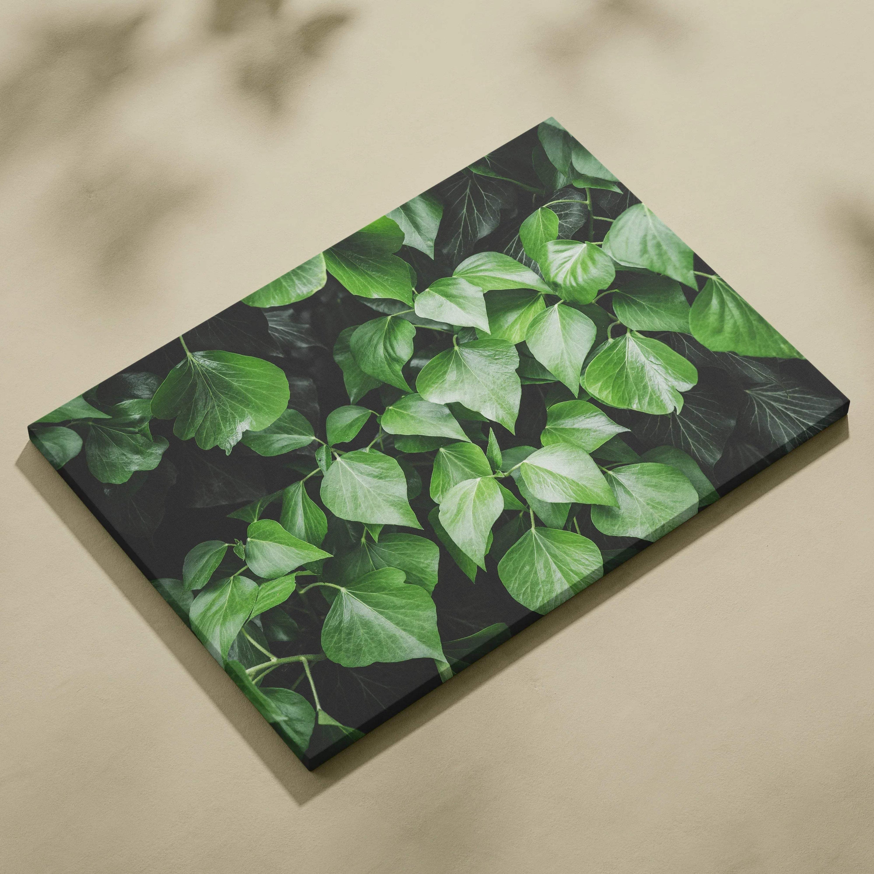 Floral wall art on canvas featuring lush green leaves with dark background decor.