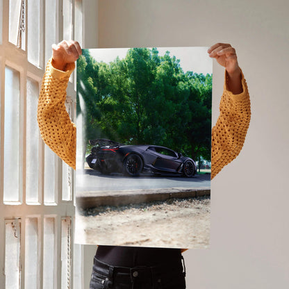 Lamborghini Revuelto poster showing sleek black sports car against green trees, perfect wall art.