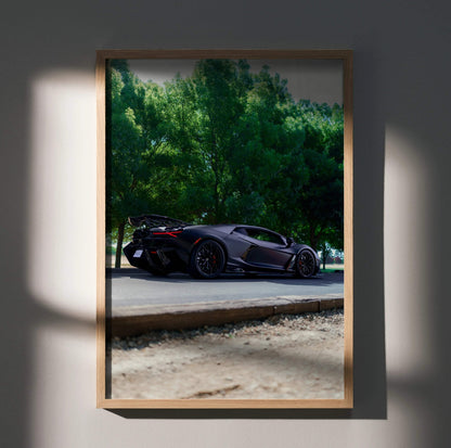 Lamborghini Revuelto black sports car poster wall art with green trees background.